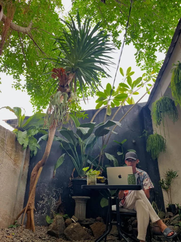 Setiawan Chogah bekerja dengan laptop di halaman Rumah Chogah 2.0